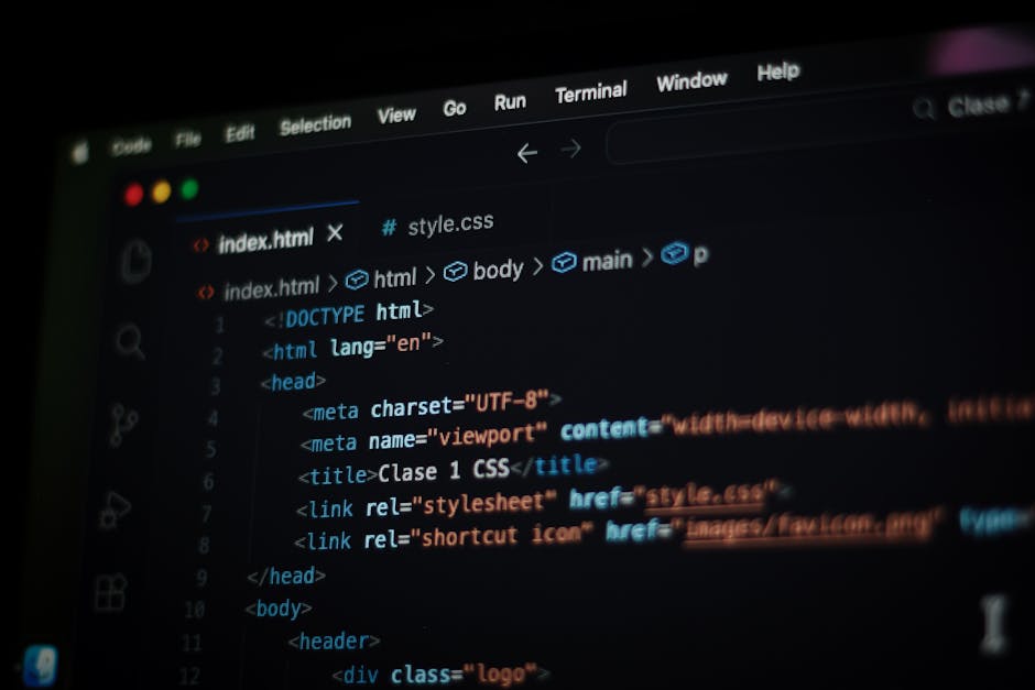 A close-up image shows a person's hand using a laptop computer on a wooden desk, with the screen displaying lines of code in a text editor. The person's wrist is adorned with a black watch, and the li